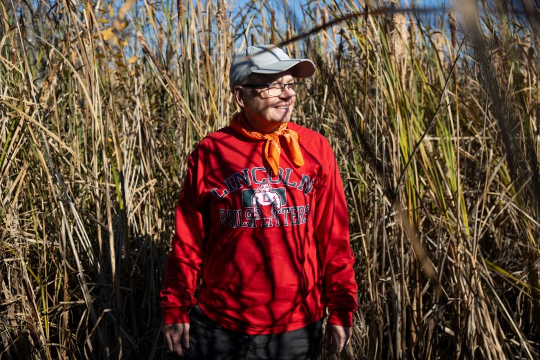 Woman in red sweatshirt and gray hat in a field with plants rising above her head