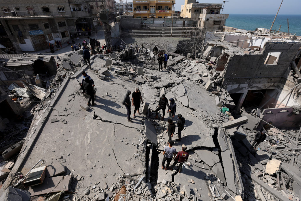 Palestinians inspect the site of an Israeli strike on a residential building, in Deir Al-Balah