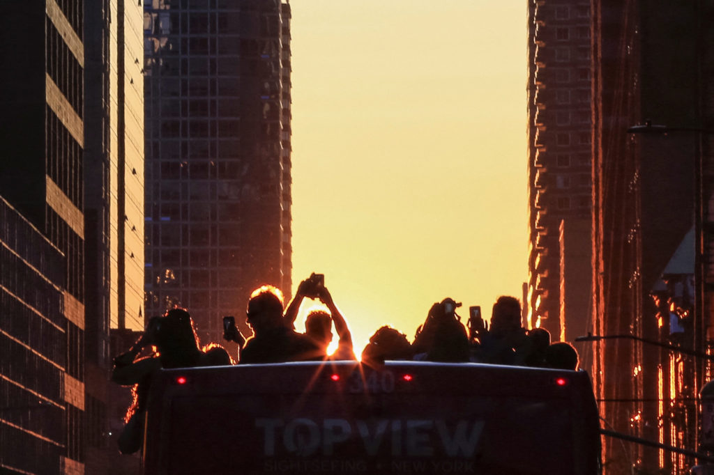 People take pictures of the sun setting over Manhattan aligned exactly with the streets in a phenomenon known as "Manhatta...
