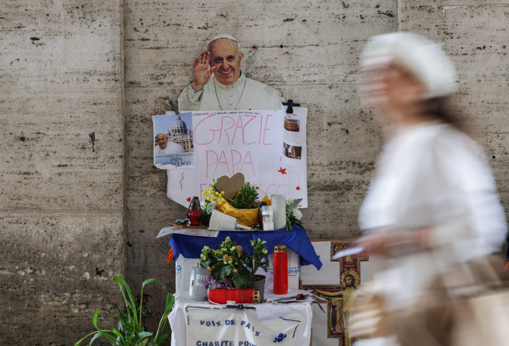 A person walks past an images of late Pope Francis, in Rome
