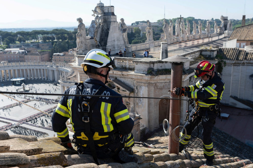 Firefighters install a chimney on the roof of the Sistine Chapel, ahead of the conclave
