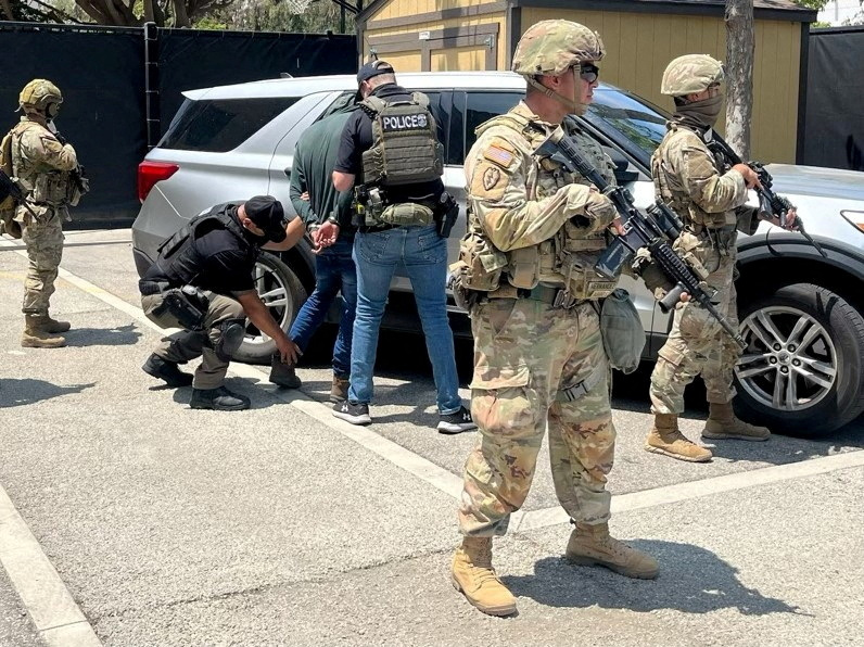 Police officers detain a person at a location given as Los Angeles