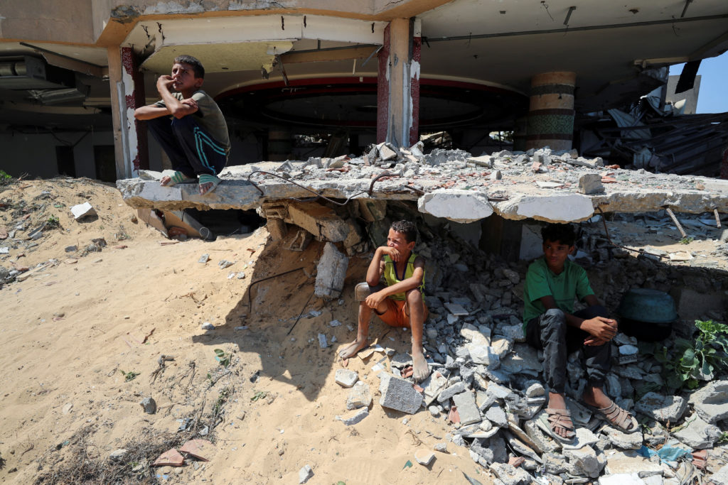 Palestinian boys rest amidst the rubble of a house previously destroyed during the Israeli military offensive, in Gaza City