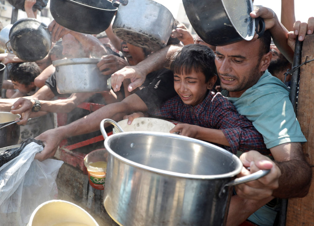 Palestinians wait to receive food from a charity kitchen, in Gaza City