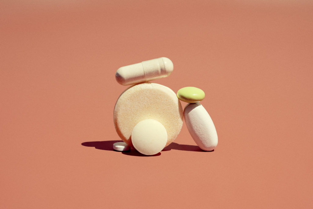 A group of pharmaceutical drugs pills laid in a pile on an orange background