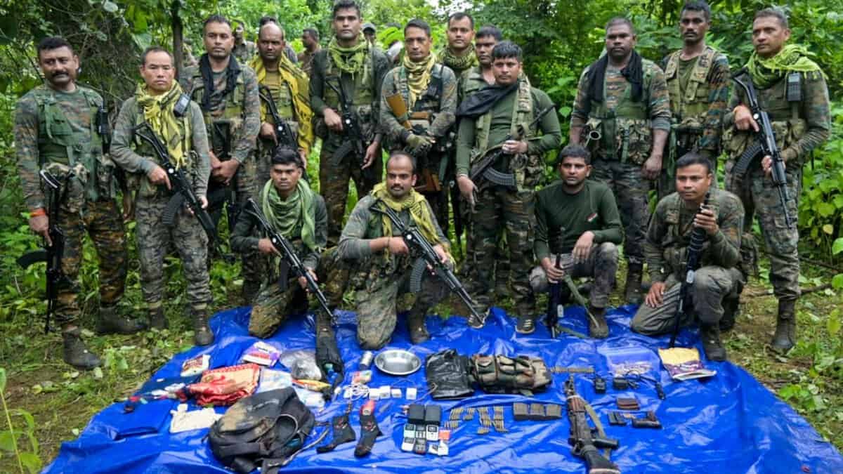 Security personnel with the arms, ammunition and other items recovered from Maoists during a gunfight
