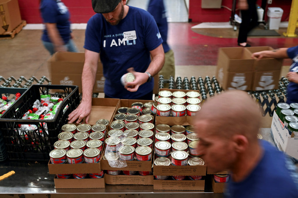 Volunteers pack boxes of food along an assembly line at the Food Bank of the Rockies Distribution Center