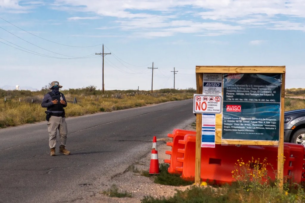 A masked guard blocks the entrance to Camp East Montana, a migrant detention facility at Fort Bliss in El Paso, Nov. 15, 2025.
