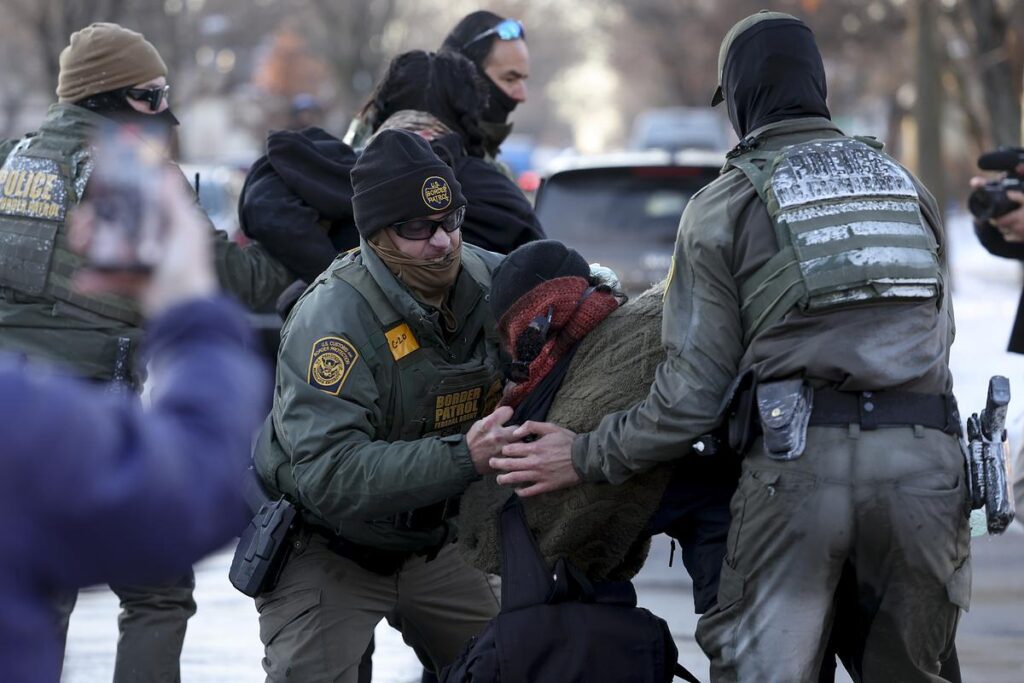 masked federal agents throw a protestor to the ground at a high school