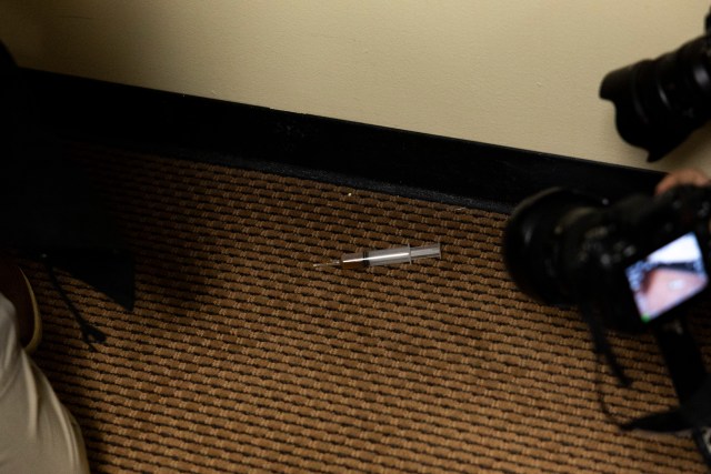 A syringe lying on carpet.