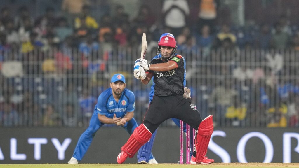 An Afghan cricketer batting during the match against Canada, with a Canadian player in the background, in.