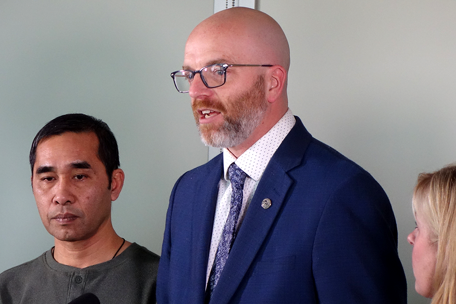 a bald man in glasses and a blue suit speaks