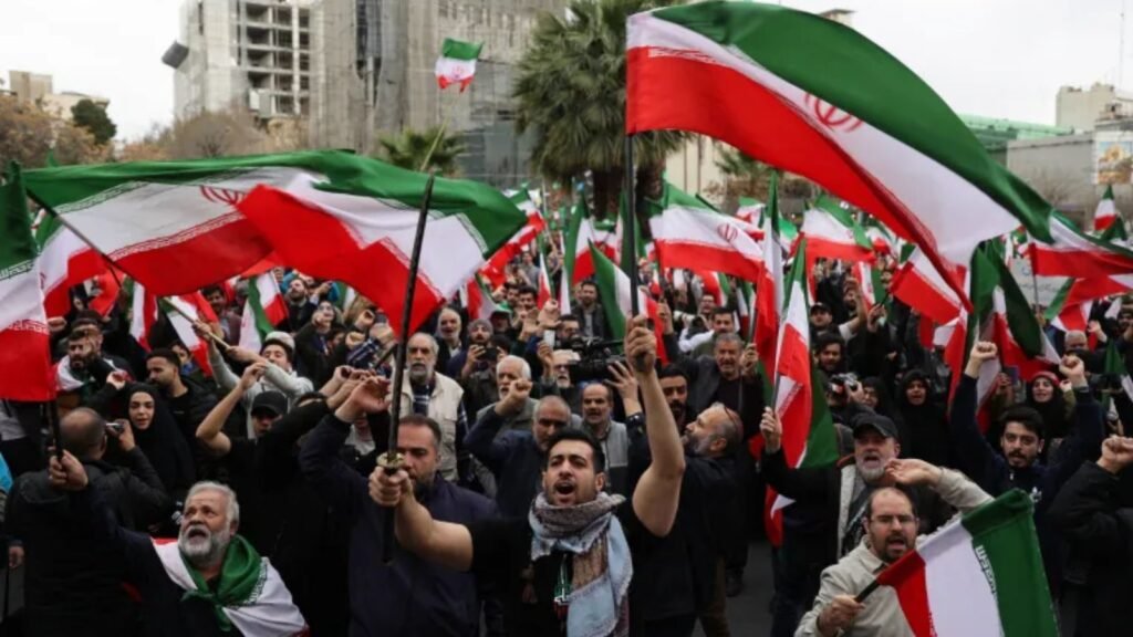Protesters hold Iranian flags during a demonstration, expressing national pride amid political tensions.
