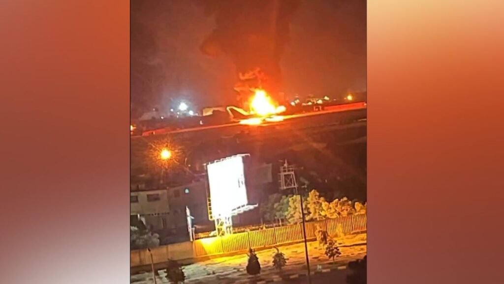 Explosion and fire on a highway during a conflict, with smoke rising into the sky.