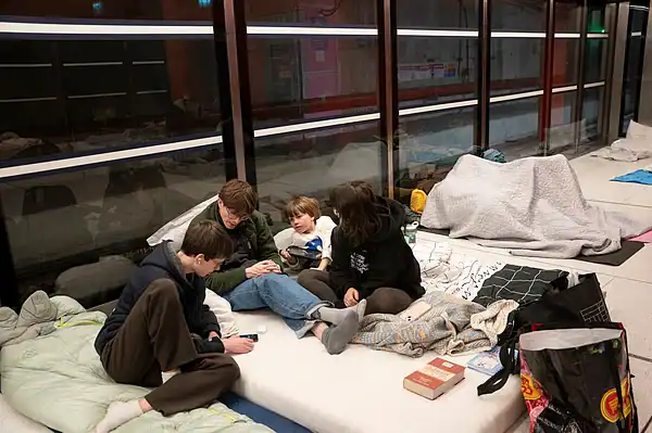 Children and adults sit on mattresses and blankets inside a metro station while waiting overnight.