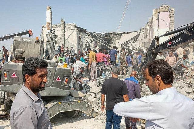 Rescue workers and civilians search through rubble after a strike hit a girls’ school in Minab, southern Iran, as heavy machinery clears debris.