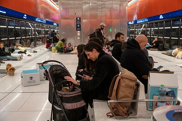 Passengers rest inside a metro station with luggage and pets as services are disrupted.