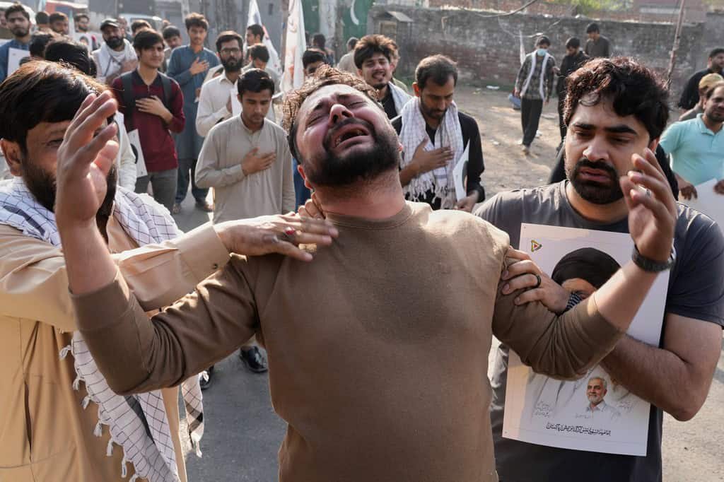 A man mourns as Shiite Muslims march holding portraits in Lahore.