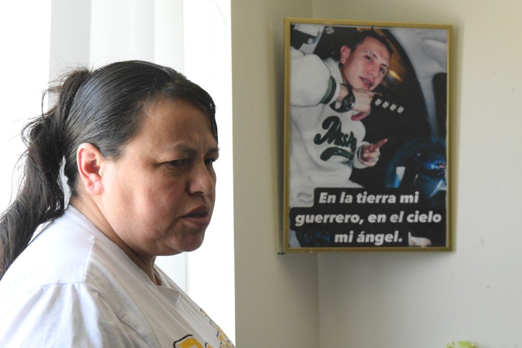A woman stands in front of a framed photo of a child.