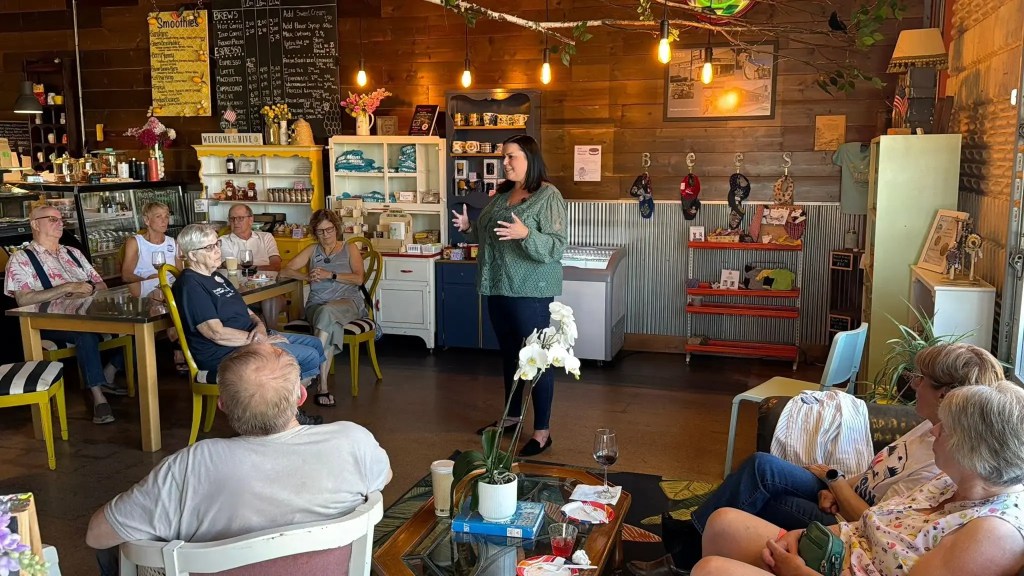 woman speaking to a group of people seated in a coffee shop